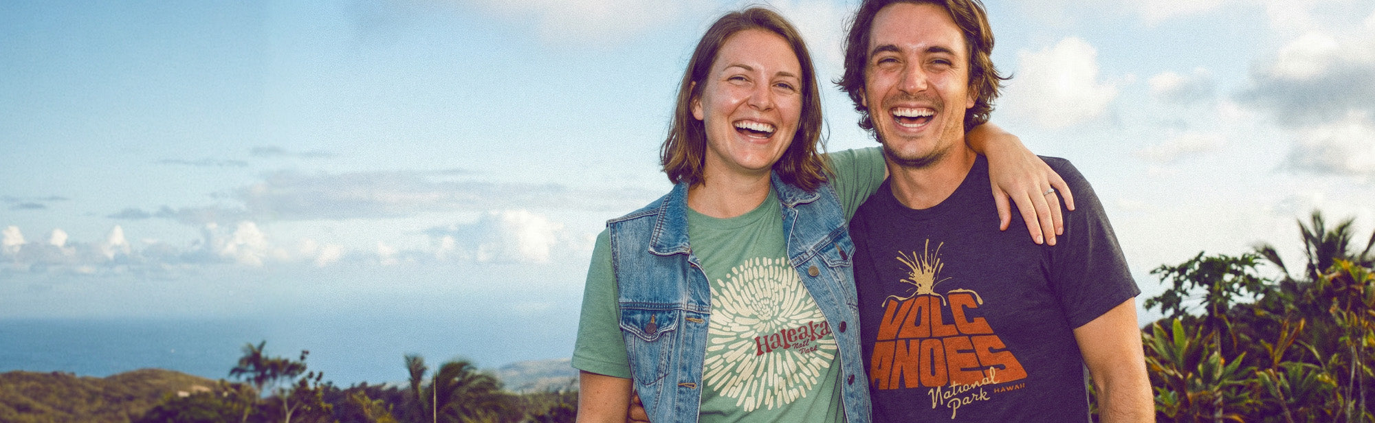 two friends hugging while wearing Hawaii themed HomeTown Riot shirts.